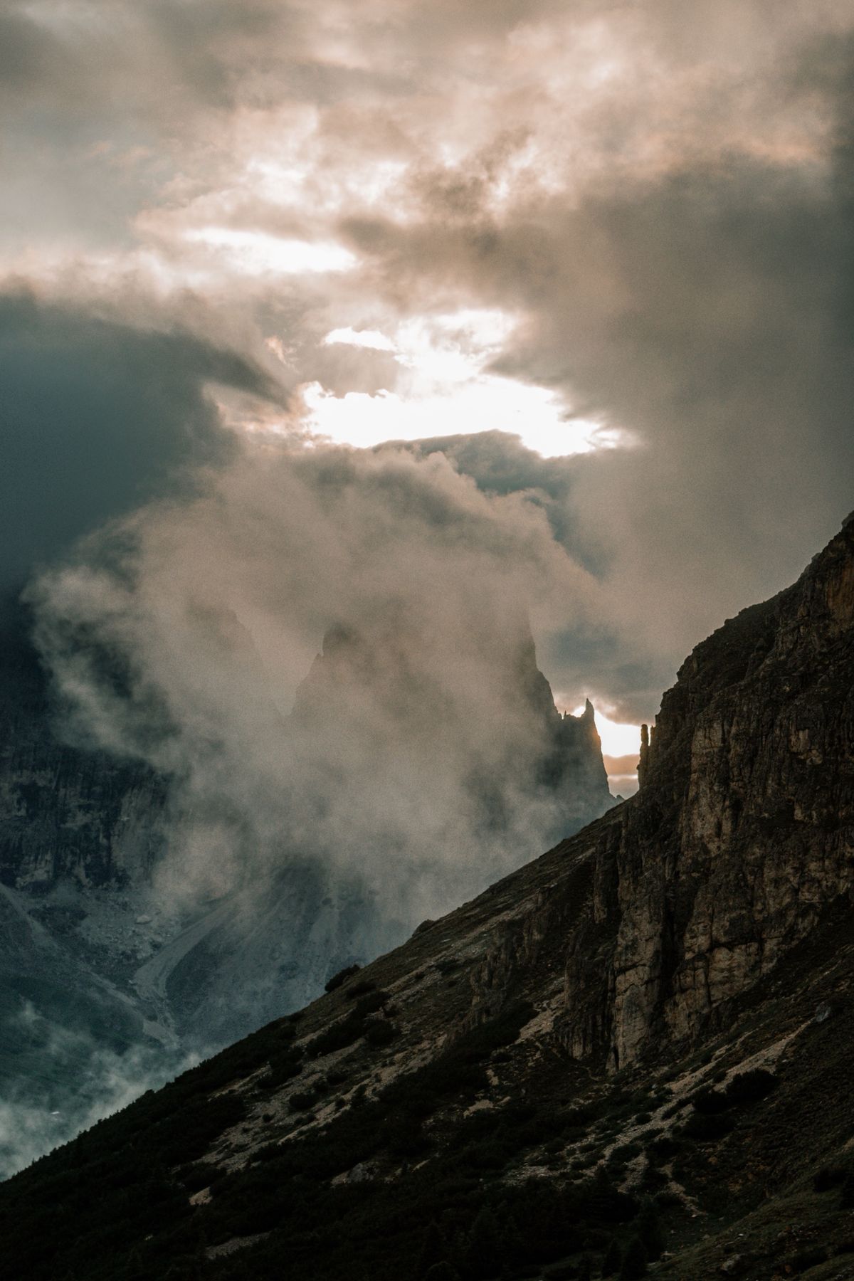A rock spire half hidden in drifting cloud as the sun breaks through
